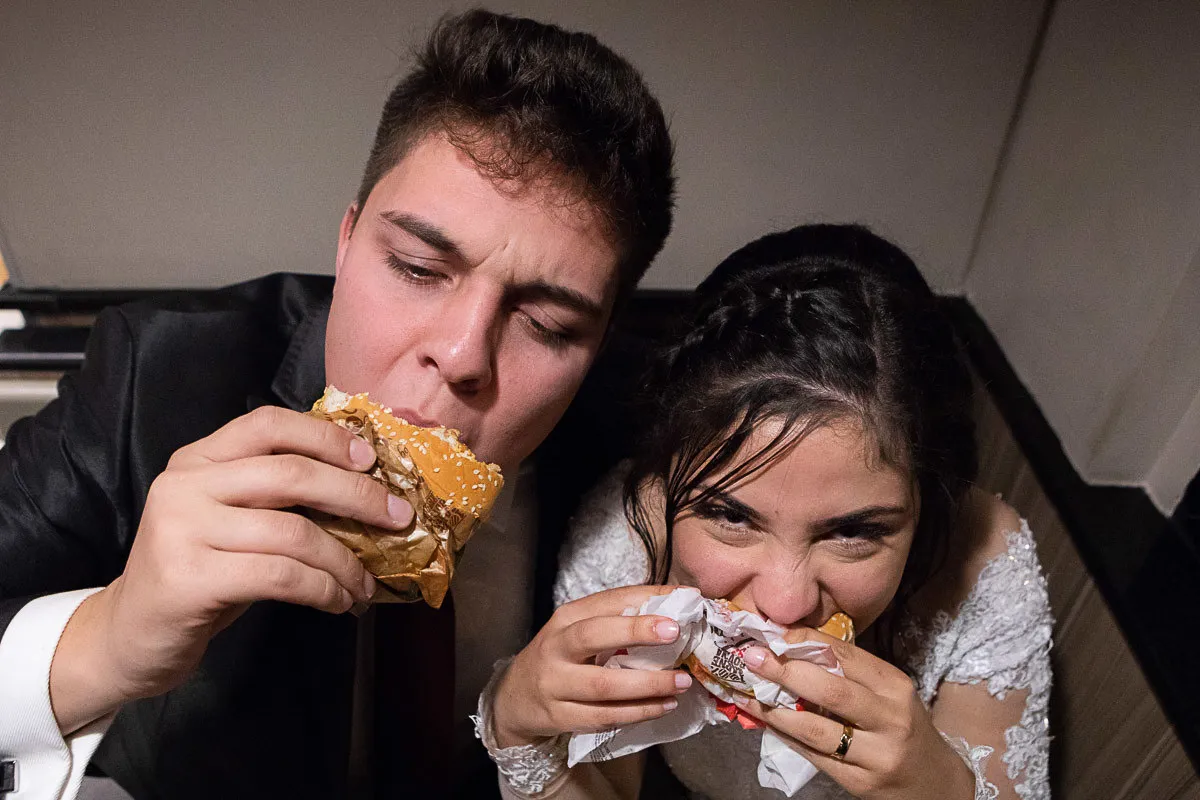 Momento descontraído comendo hambúrguer, quebrando o tom formal.